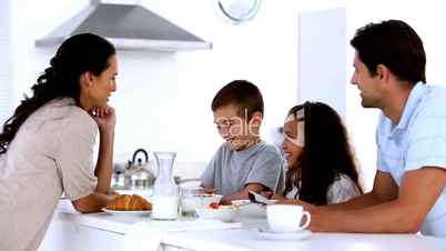 Mother chatting to children at family breakfast and pouring milk