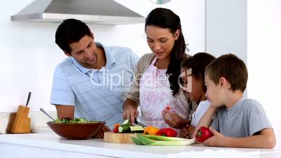 Mother showing children how to chop vegetables