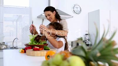 Mother and daughter tossing salad together