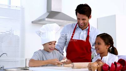 Father watching son stretch pastry with sister