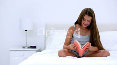 Cute girl reading a book on bed