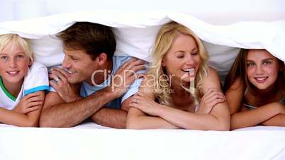 Family smiling at camera under the covers
