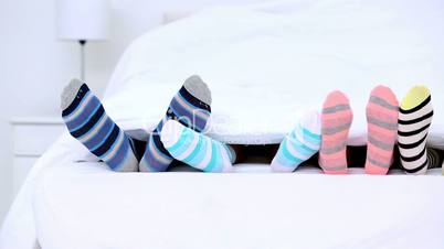 Familys feet in stripey socks kicking under the covers