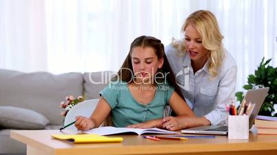 Mother helping her daughter with homework and smiling