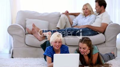 Parents relaxing on couch with children using laptop