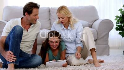 Parents and daughter using tablet on floor
