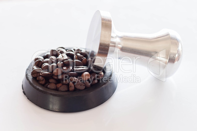 Coffee tamper and roasted coffee in rubber saucer