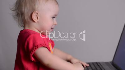 Cute baby girl using a laptop computer. Rack focus and dolly in.