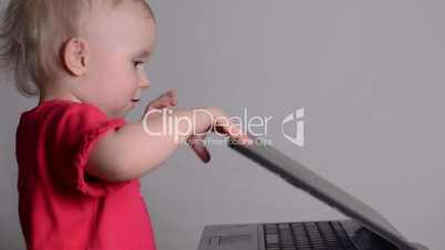 Cute baby girl using a laptop computer. Rack focus and dolly in.