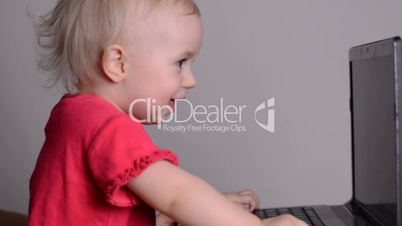 Cute baby girl using a laptop computer with mothers help