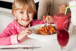 Cute kid enjoying pasta and watermelon juice