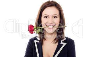 Young female holding rose between her teeth