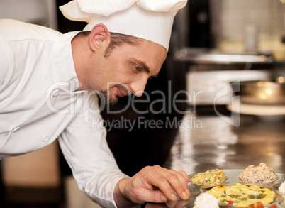 Satisfied chef analyzing dish before serving