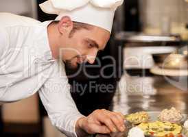 Satisfied chef analyzing dish before serving