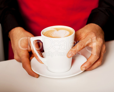 Hands of waiter serving a cup of cappucino