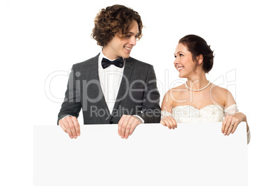Married couple posing with a blank ad board