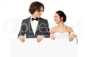 Married couple posing with a blank ad board