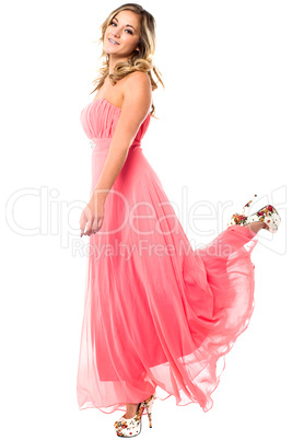 Charming girl in strapless party dress lifting leg