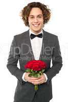 Groom in tuxedo posing with a bouquet
