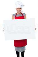 Smiling female chef holding an ad board