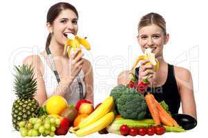 Young smiling girls eating banana