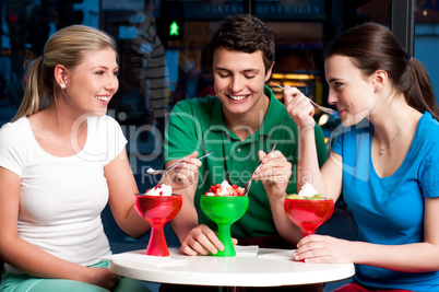 Three friends enjoying tempting dessert