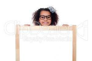 Girl peeping from behind white writing board