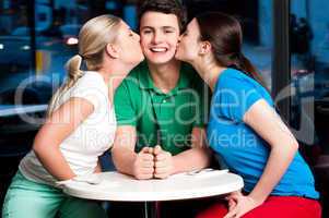 Two girls kissing handsome young boy