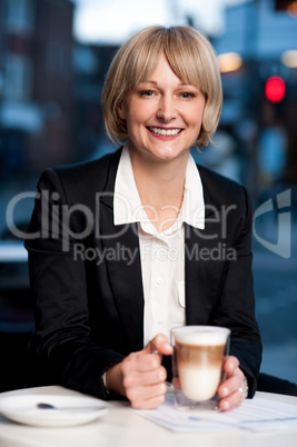 Smiling businesswoman having coffee, outdoor