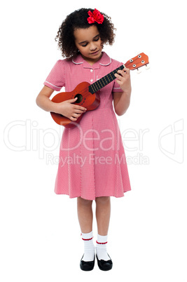 Preschool cute girl playing a guitar