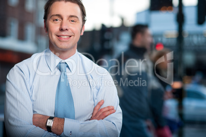 Confident businessman posing, street background