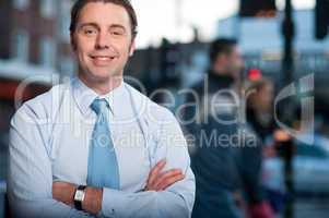 Confident businessman posing, street background