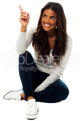 Young woman looking and pointing upwards