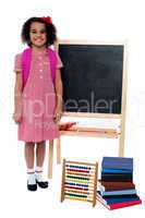 Smiling school girl standing near the blackboard