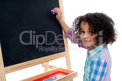 Beautiful little girl writing on classroom board