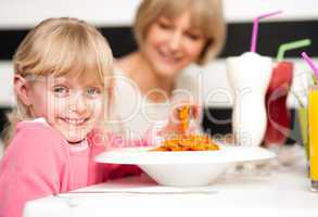Cute kid enjoying pasta and juice