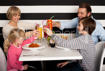 Family toasting smoothies in restaurant