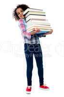 Cute cheerful child carrying stack of books