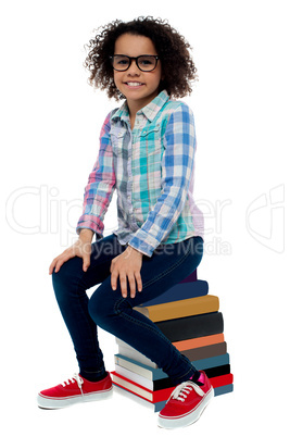 School girl sitting on stack of books