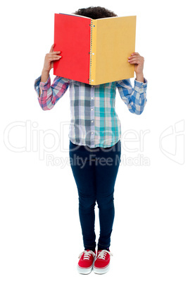 School girl hiding her face with a book