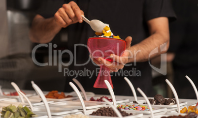 Man topping ice-cream with gems and jellies