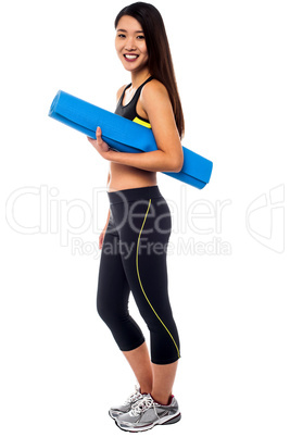 Full length portrait of slim girl holding blue mat