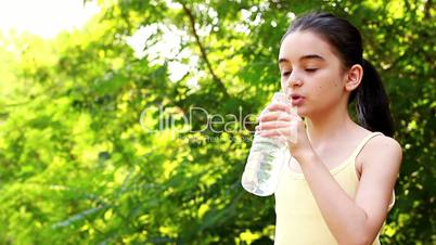 Girl drinking water in summer park