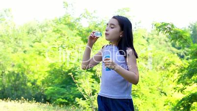 Little cute girl blowing soap bubbles