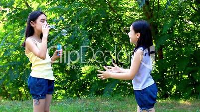Little girl blowing soap bubbles in summer park