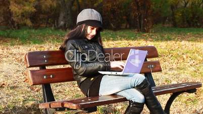 Teenager sitting on bench with laptop