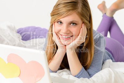 Young girl lying on bed with laptop