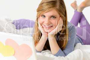 Young girl lying on bed with laptop