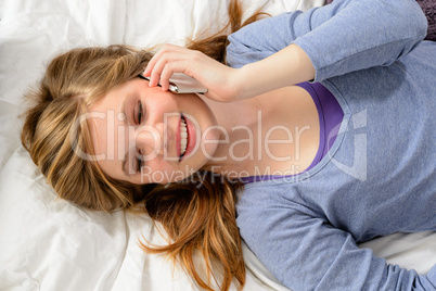 Girl lying in bed talking on phone