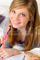 Smiling teenage girl daydreaming over her diary